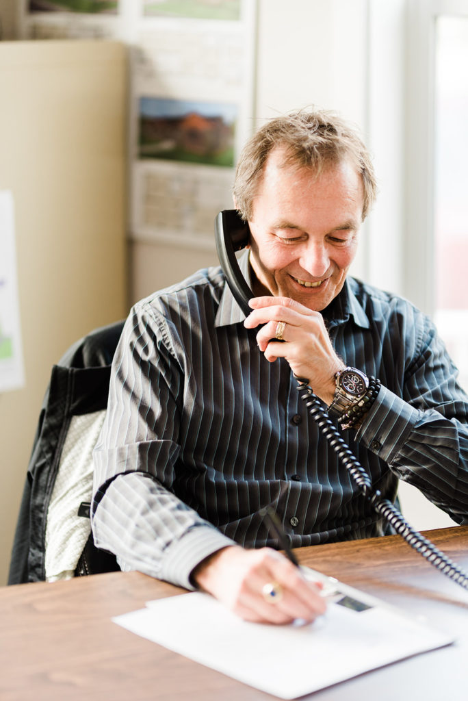 a sales guy sits at his desk and takes a phone call from perspective clients and tells them countryside manufactured homes options