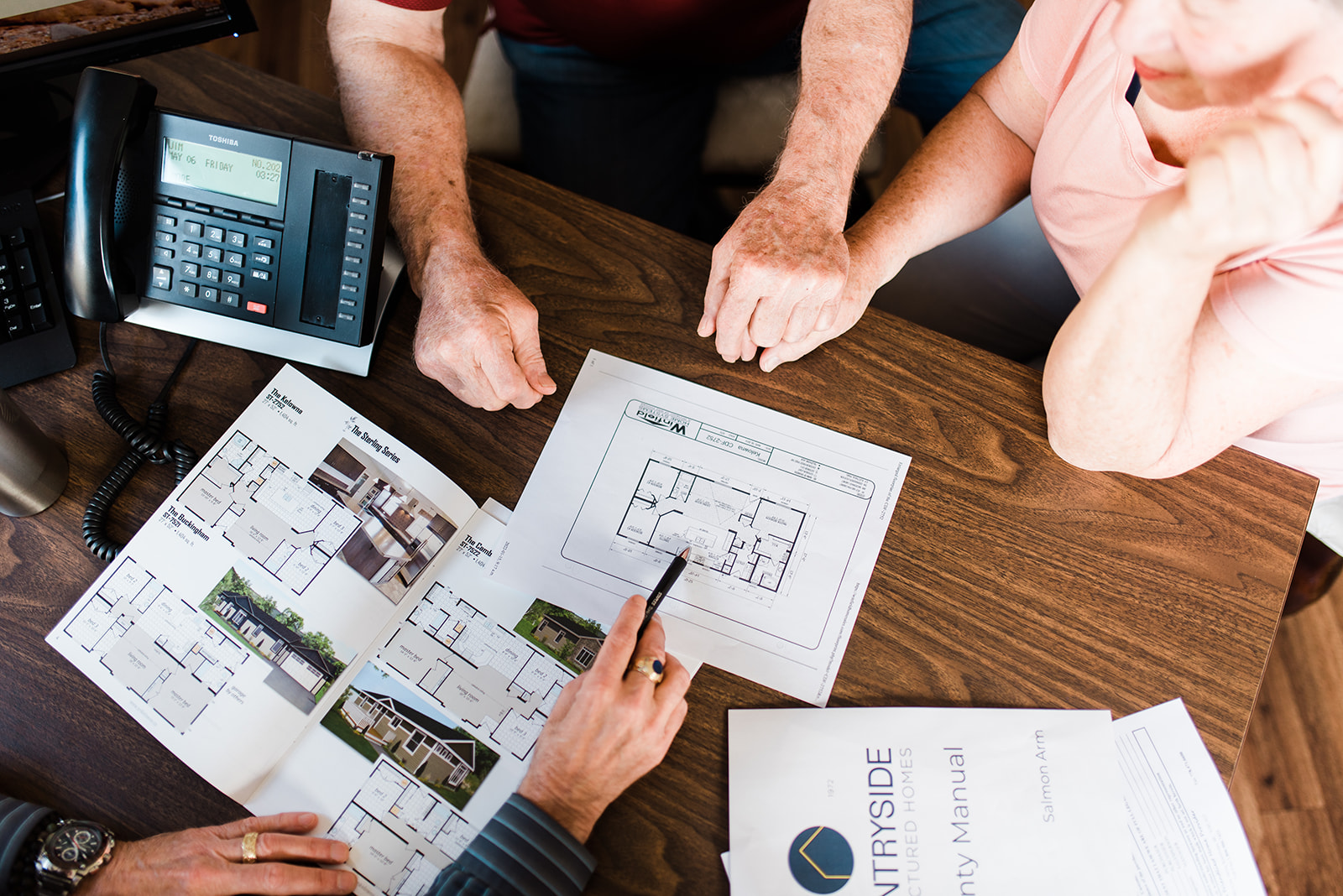 top down look at a sales rep showing a couple different prices for buying a manufactured or modular home with Countryside