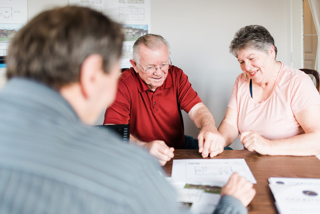 an elderly couple who has purchased a home from countryside manufactured homes sits with their sales rep going over the finalized plans and learning about countryside manufactured homes warranty
