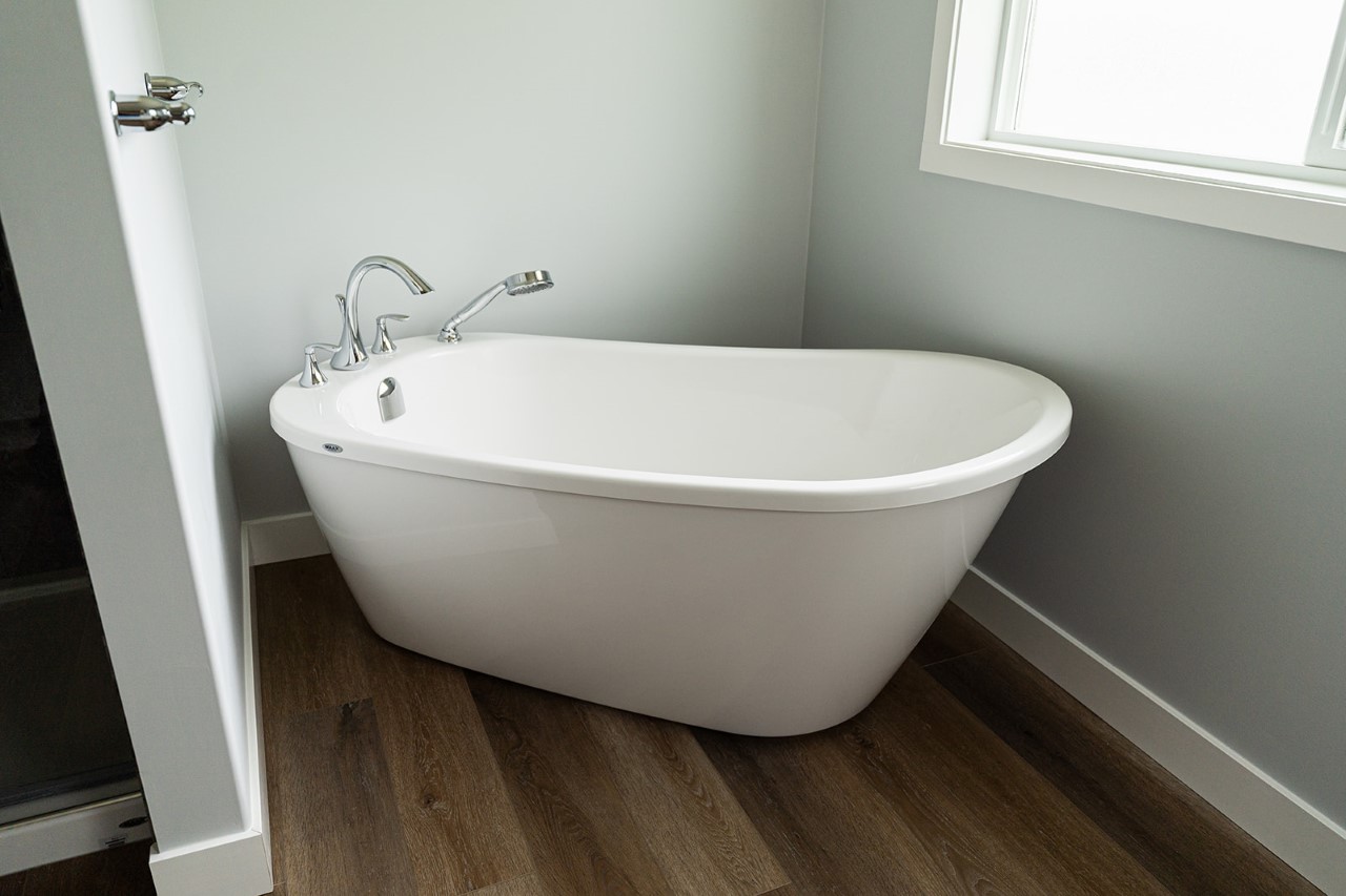 stand alone tub tucked in beside the open and airy glass and tile shower in the kent showhome