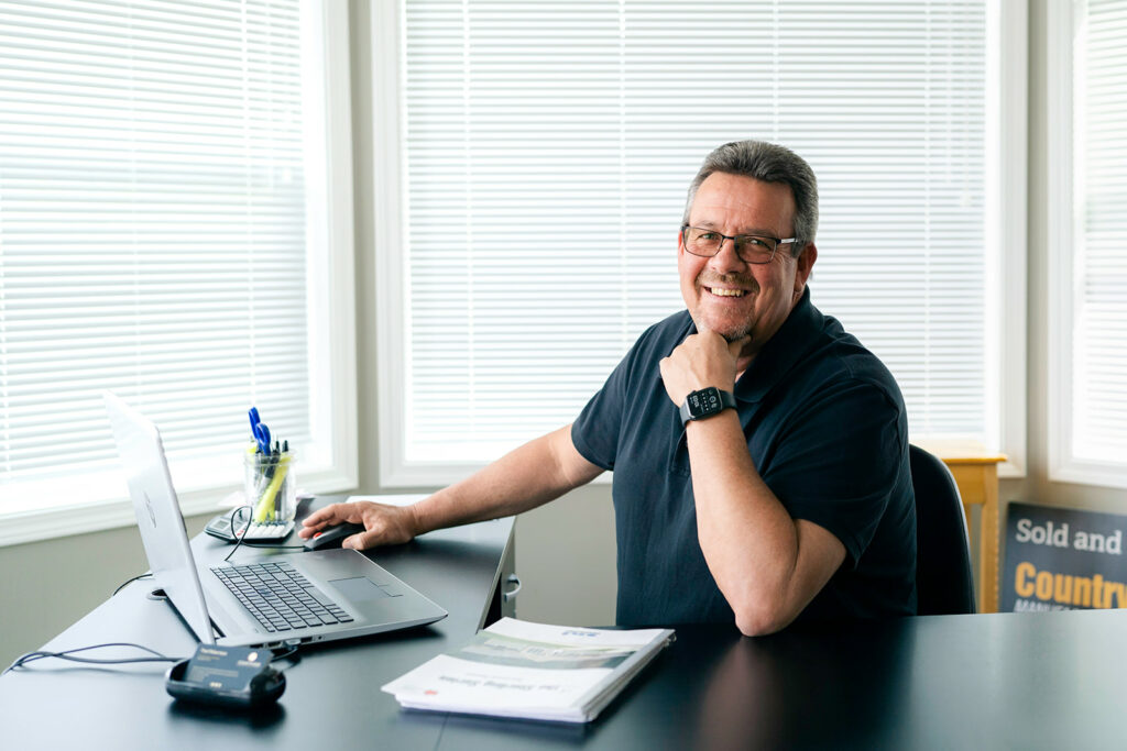 Family-owned manufactured home sales advisor sitting at his desk ready to help you find your perfect customized home in BC